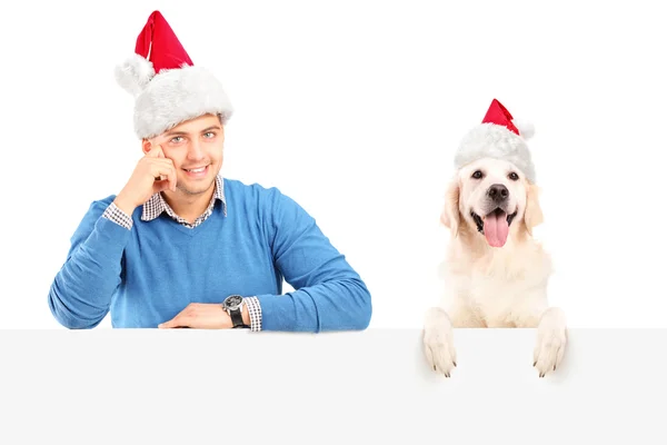 Cara e cachorro vestindo chapéus de Papai Noel — Fotografia de Stock