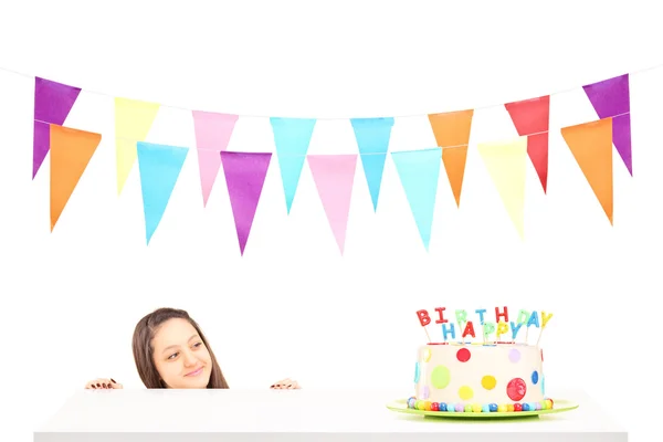Una ragazza di compleanno con un cappello da festa guardando una torta di compleanno — Foto Stock