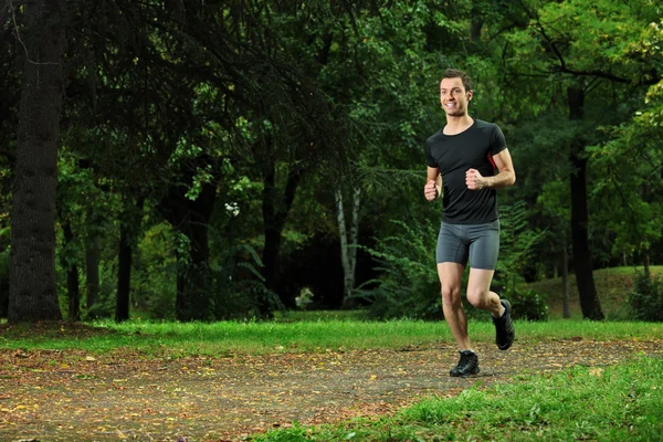 Manliga friidrottare jogga i parken — Stockfoto