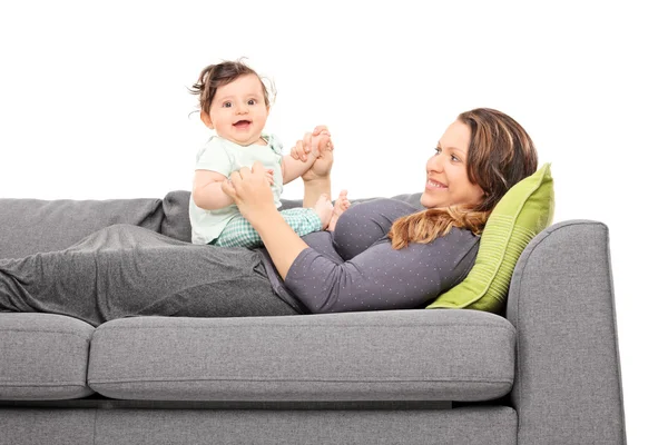 Женщина лежит на диване и смотрит на свою дочь — стоковое фото