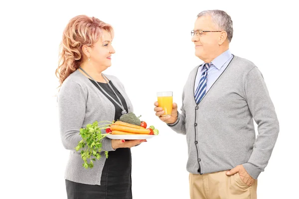 Casal segurando prato cheio de legumes — Fotografia de Stock