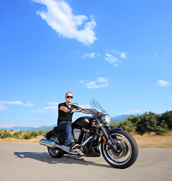 A biker riding a customized motorcycle on an open road — Stock Photo, Image