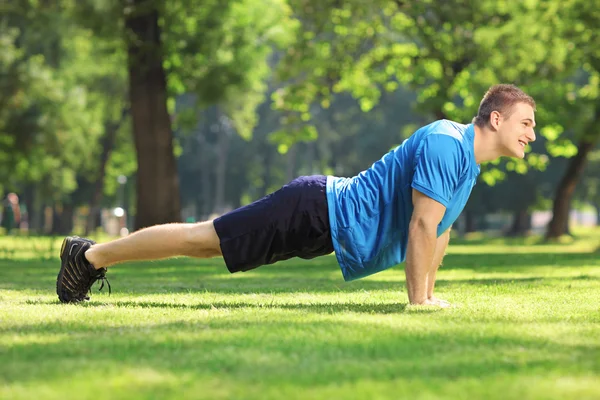 Handsome sportsman exercising in a park — Stock Photo, Image