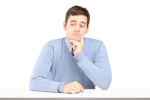 Besorgter junger Mann sitzt am Schreibtisch — Stockfoto