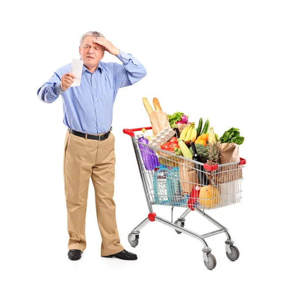 Geschokt senior kijken naar winkel ontvangst — Stockfoto