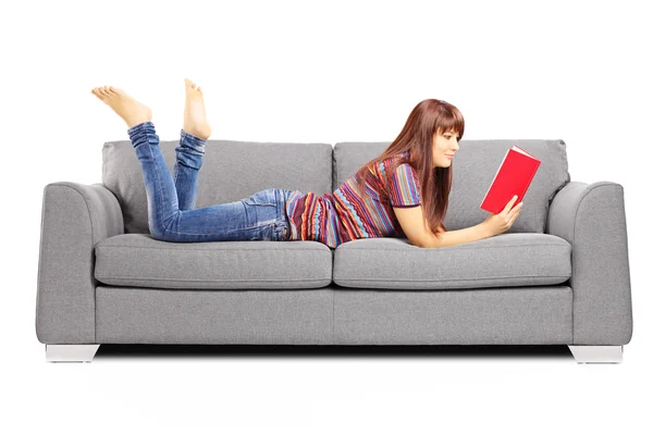 Femme sur un canapé lisant un livre — Photo
