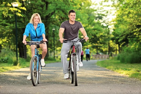 Happy couple biking in park — Stock Photo, Image