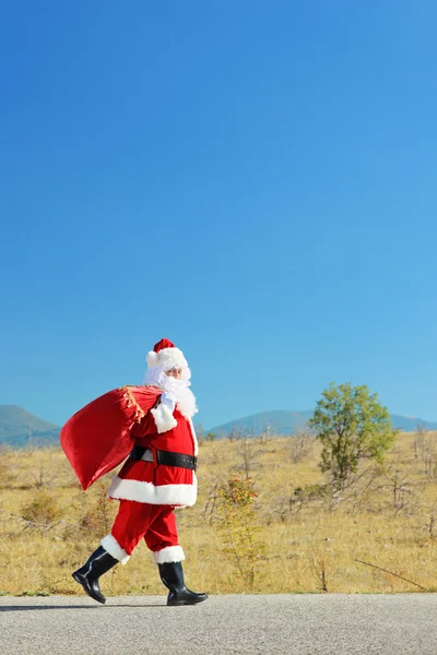Santa claus walking on an open road — Stock Photo, Image