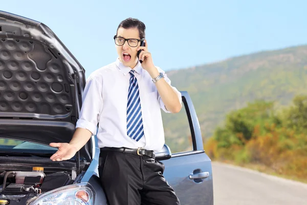 Hombre nervioso de pie junto a su coche roto y hablando en un pho —  Fotos de Stock