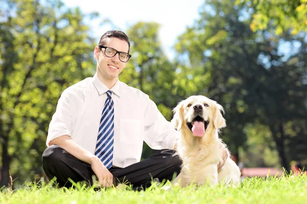 Killen som sitter bredvid hunden i park — Stockfoto