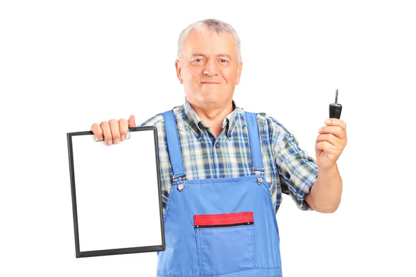 Mechanic holding car key and clipboard — Stock Photo, Image