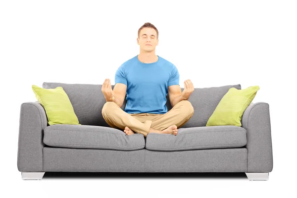 Männchen meditiert sitzend auf einem Sofa — Stockfoto
