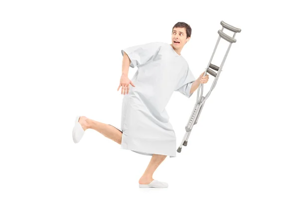Scared patient running holding crutch — Stock Photo, Image