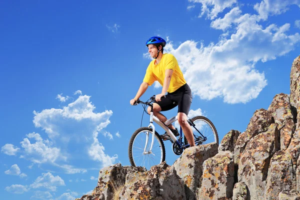 Biker riding bike on rocks — Stock Photo, Image