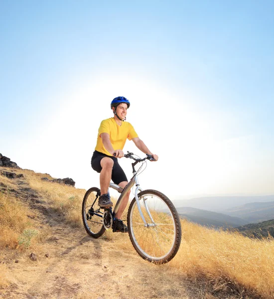 Un ciclista montando una bicicleta de montaña en un camino sucio — Foto de Stock