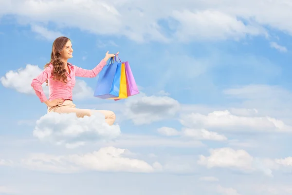 Female flying on cloud and holding bags — Stock Photo, Image