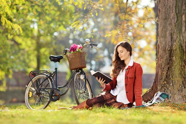 Frau mit Fahrrad liest Roman — Stockfoto