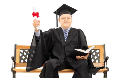 Mature man in graduation gown on bench clipart