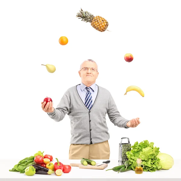 Homem maduro malabarismo frutas — Fotografia de Stock