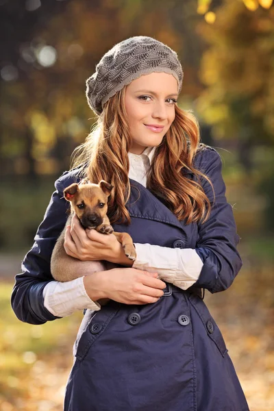 Mujer sonriendo y sosteniendo cachorro — Foto de Stock