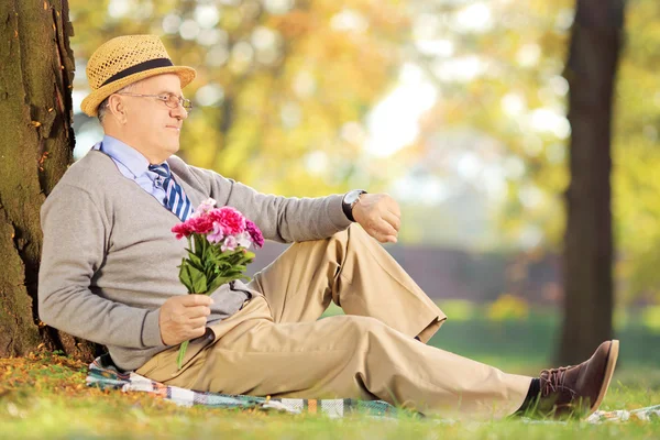 Senior met bloemen tijd controleren — Stockfoto