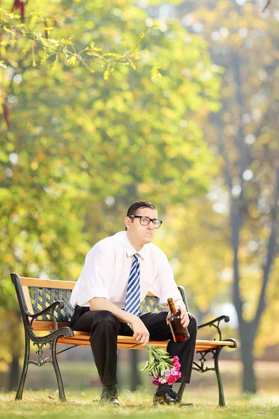 Hombre bebiendo alcohol sosteniendo flores — Foto de Stock