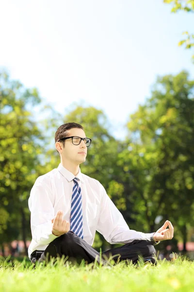Businessperson meditating on a grass — Stock Photo, Image