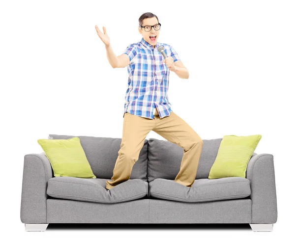 Guy with microphone singing on sofa — Stock Photo, Image
