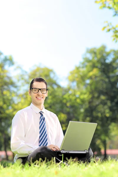 Zakenman die op laptop in park werkt — Stockfoto