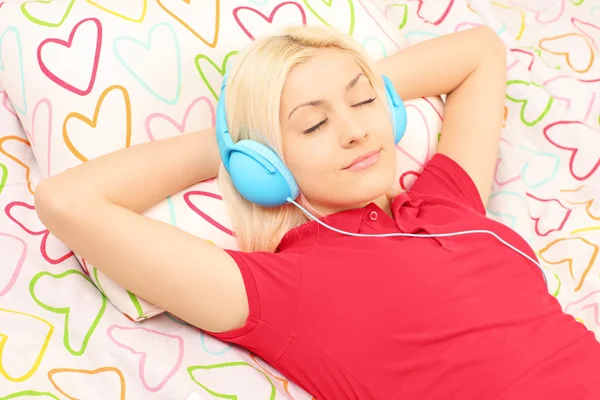 Weibchen im Bett und Musik hören — Stockfoto