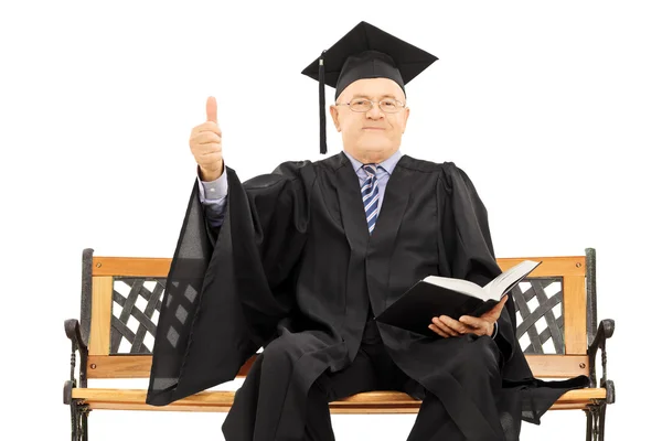 Man in afstuderen gown duim omhoog — Stockfoto