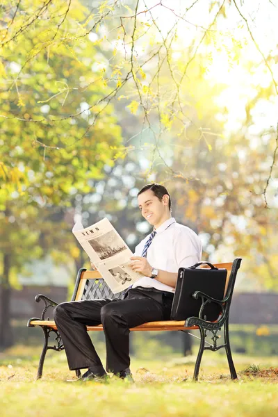 Man on a bench reading a newspaper — Stock Photo, Image