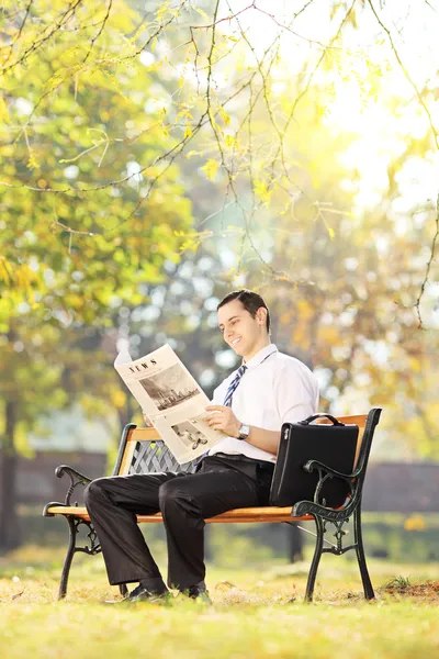 Man på en bänk som läser en tidning — Stockfoto