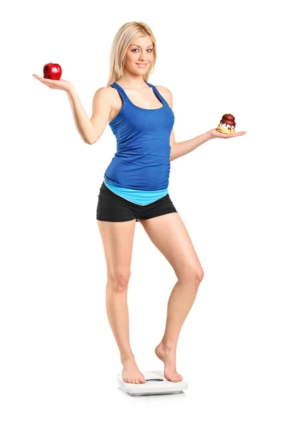 Woman holding an apple and cake — Stock Photo, Image