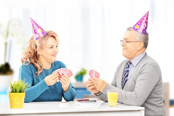 Couple avec chapeaux de fête jouant aux cartes — Photo