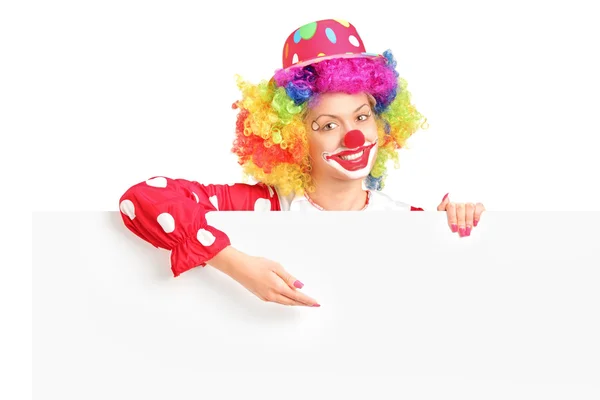 Vrouwelijke clown achter witte paneel — Stockfoto