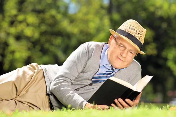Senior herre med en bok i parken — Stockfoto