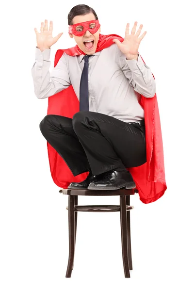 Aterrorizado superhéroe de pie sobre una silla — Foto de Stock