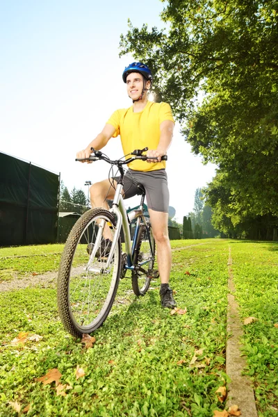 Man standing on a bike in a park — Stock Photo, Image