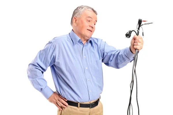 Confused senior holding electronic cables — Stock Photo, Image