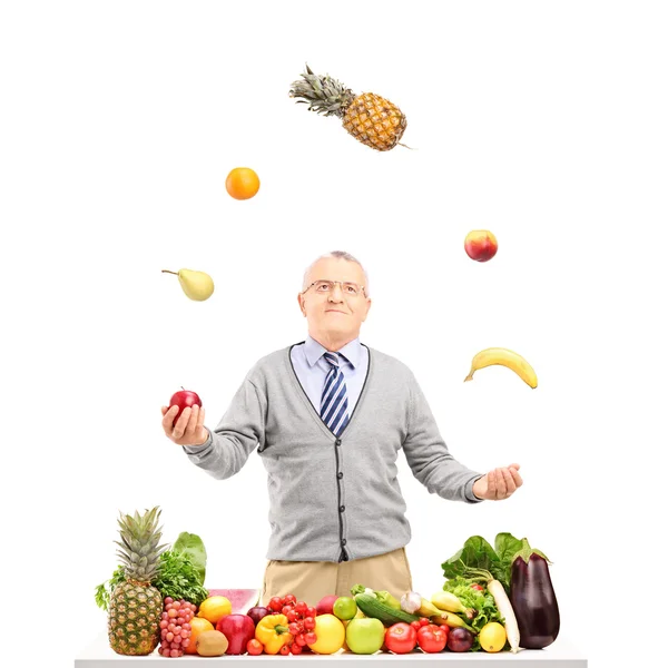 Mature man juggling fruits — Stock Photo, Image