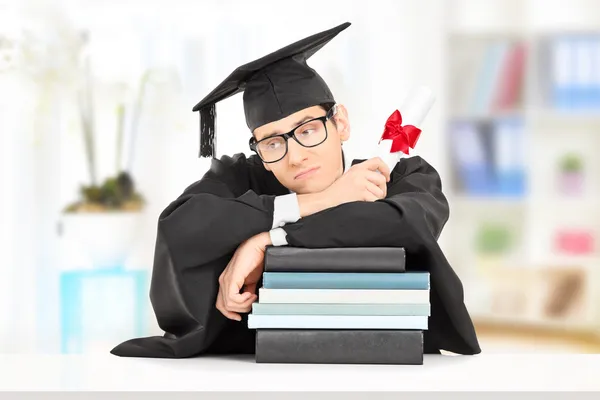 Preocupado graduado universitario en libros — Foto de Stock