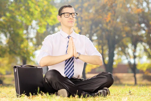 Uomo d'affari con gli occhiali che fanno esercizio di yoga seduto su un — Foto Stock