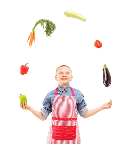 Chłopiec z fartuch żonglerka z warzywami — Zdjęcie stockowe