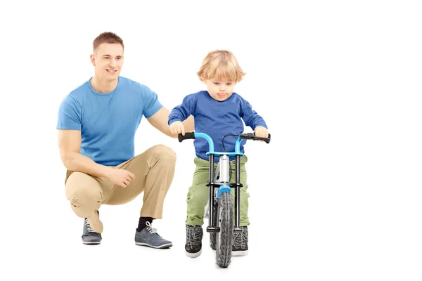 Отец рядом с сыном катается на велосипеде — стоковое фото