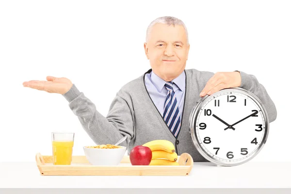 Senior gentleman holding a clock and gesturing — Stock Photo, Image