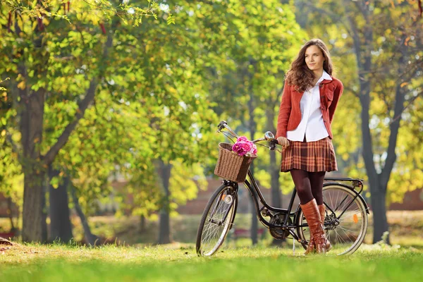 Kvinna poserar i parken med cykel — Stockfoto