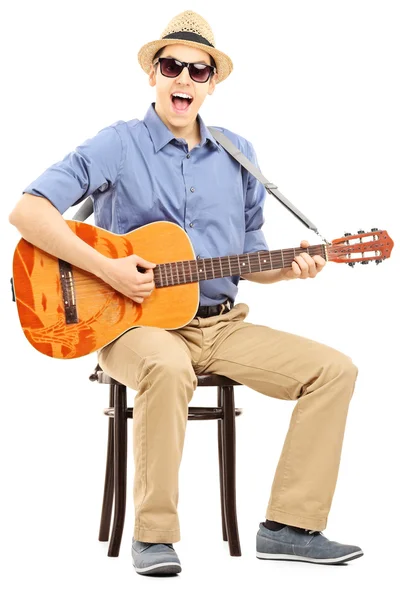 Hombre en silla y tocando la guitarra acústica — Foto de Stock