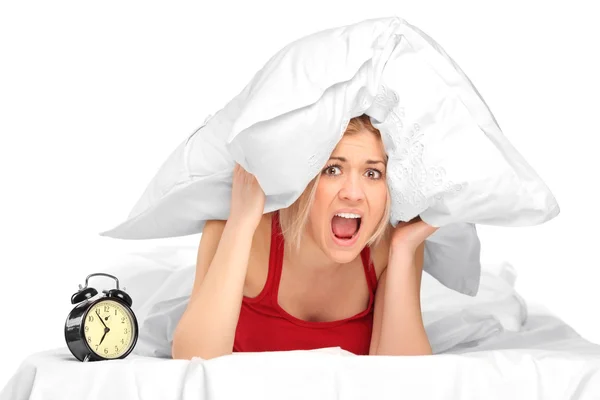 Woman screaming and covering her ears with pillow — Stock Photo, Image