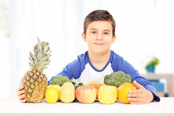 Jongen zitten met groenten en fruit — Stockfoto